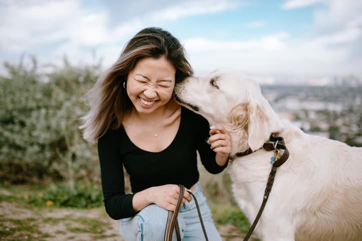 woman gets canine kisses and wonders why do dogs lick ears